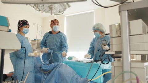 The surgeon's doing laparoscopic surgery in the operating room. Minimally invasive surgery. Laparoscopic instrument. Portrait of focused doctor in sterile gloves holding laparoscopic instrument.