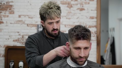 Man barber cutting hair of male client with clipper at barber shop. Hairstyling process. Slow motion Close up. High quality FullHD footage