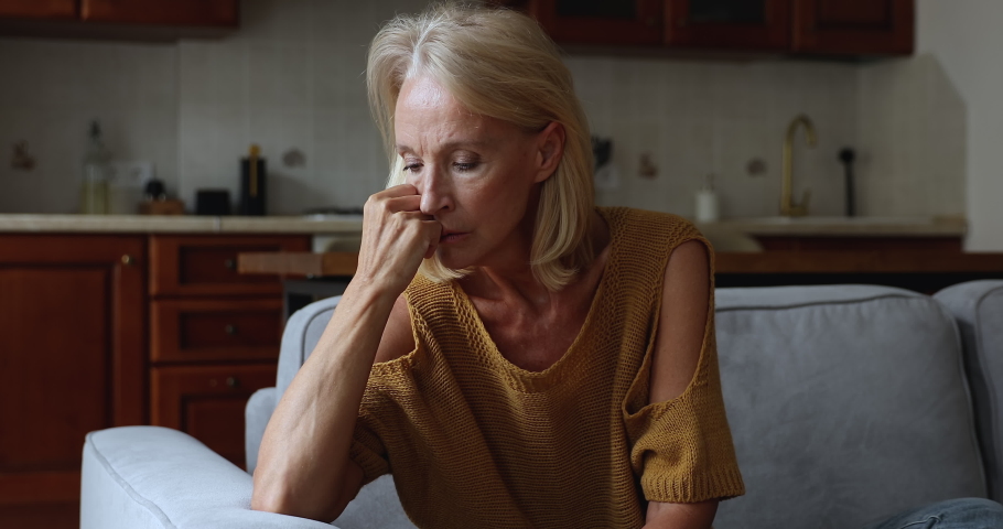Sad concerned mature woman sit on sofa looks upset, deep in sad thoughts, feels unhappy, suffers from break up or divorce, marriage split, having life troubles. Lonely older female portrait concept | Shutterstock HD Video #1088649235