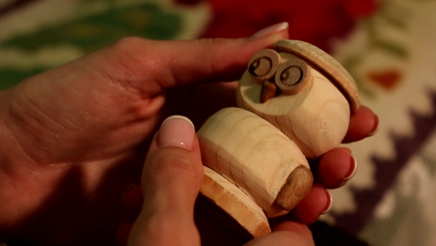 A woman holds an owl-shaped wooden toy
