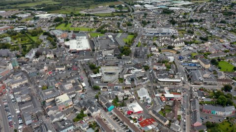 Aerial panoramic footage of town. Central borough with squares and cathedral. Tilt up reveal of landscape and cloudy sky. Ennis, Ireland