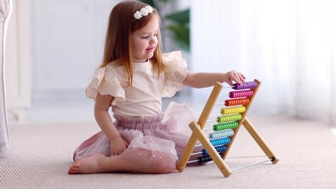 cute baby girl playing with colorful abacus toy on the carpet at home