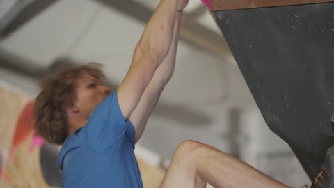 HANDHELD, climber training on a climbing wall, practicing rock-climbing and moving up.