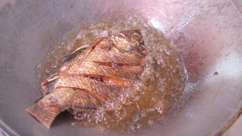 Close up of frying tasty large fried nile tilapia fish in hot pan