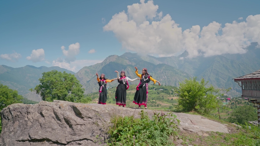 Young beautiful cheerful Indian Asian Women or females wearing traditional attire dancing outdoors with a background of Mountainous valley in daylight. Concept of customs, music, culture, traditions | Shutterstock HD Video #1088659747