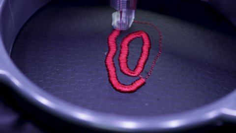 Machine embroidery of the letter "O" on black leather with red thread. Machine embroidery design, close up 4k video.