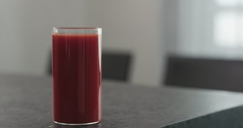 Slow motion man hand take tomato juice in highball glass from concrete countertop