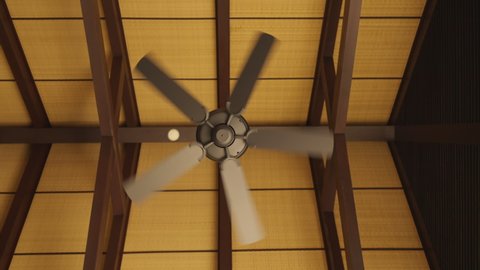 brown indoor ceiling fan on an exposed wooden support beam, with a decorate wooden ceiling, in the hall of living room of a contemporary home interior,home interior design concept