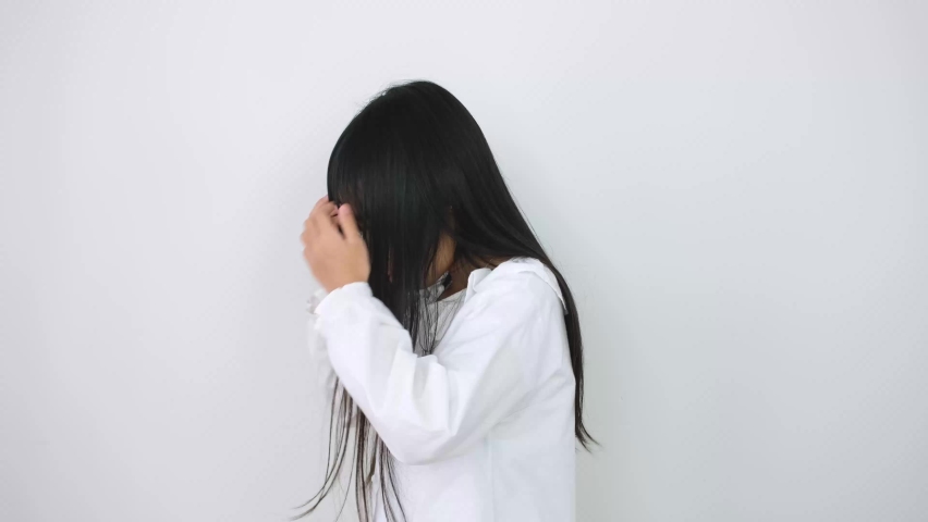 Young Asian girl wearing a white shirt smiling brightly on a white background.