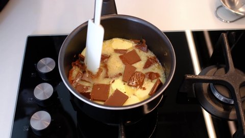 Melting and mixing a piece of butter in a saucepan on the gas stove, butter becoming liquid. Process melt chocolate