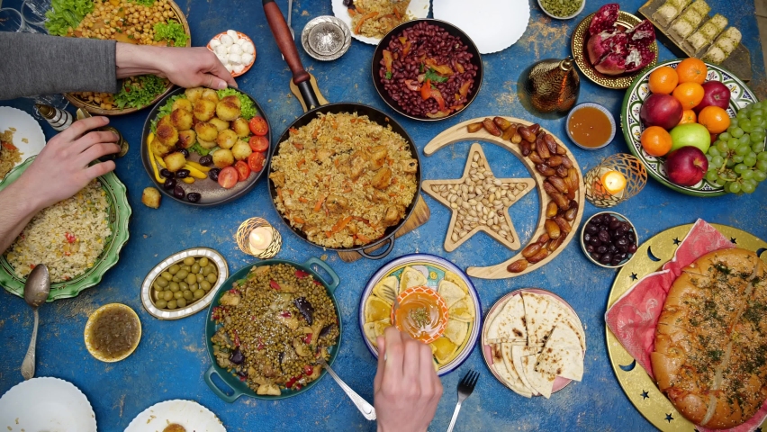 Family Ramadan dinner. Muslim people gathering to break their fast together. Traditional Dishes to Serve During Ramadan. A people sitting at a table, top view | Shutterstock HD Video #1088662749