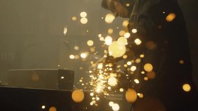 Industrial worker cutting metal with many sharp sparks. Male using special tool for cutting metal at workshop. Sparks flying from metal processing. Slow motion. 4K video. Shot on RED