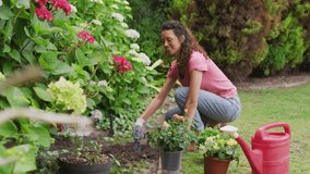 Animation of white circles spinning and glowing spots over happy biracial woman gardening. gardening and community garden week concept digitally generated video.