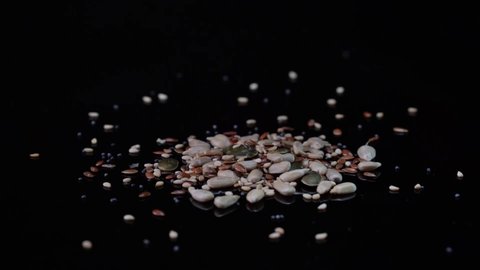 Horizontal video, close-up of sprinkling sesame seeds, brown flax, poppy, pumpkin seeds and sunflower seeds, which are high in fibre and omega 3.