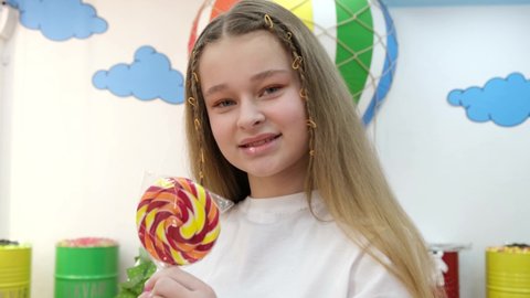 Girl holding a lollipop. Beautiful happy blond girl holding a colored lollipop.