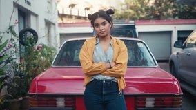 A young modern stylish retro smiling Indian Asian woman or girl is standing outdoors leaning on red vintage car and looking at camera in a city setting. Concept of youth, ambition, rebel, revolution - Powered by Shutterstock - Get 15% off with code: PIKWIZARD15