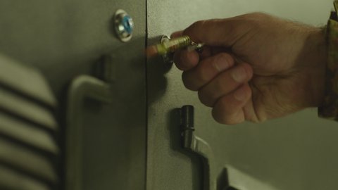 4K Close up view of green colored metallic military Locker Room . Soldiers putting bag inside safe and locking door . Military dressing room , storage . Key rotation