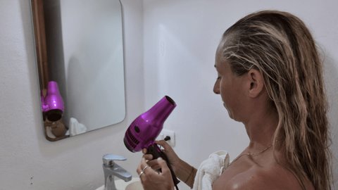 Woman blowdrying her hair at home