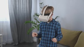 Boy playing games with VR headset. Enjoying time at home. Experiencing virtual reality. Kid wearing VR headset, moving hands and touching air. Digital education or virtual reality learning