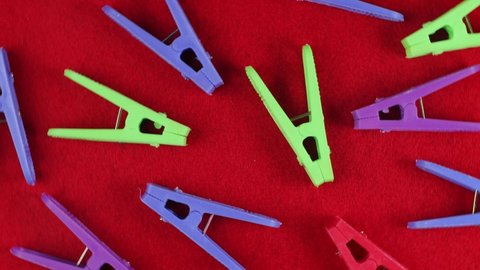 Colored clothespins on a red textured background, top view, close-up, bright backdrop.