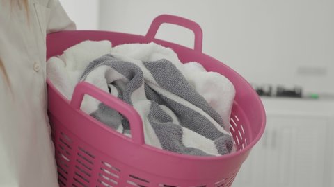 young woman holding basket with dirty clothes, laundry service, close-up.
