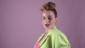 Young, beautiful woman professional make up artist with lipstick marks smile at pink background, fashion blogger blows away pink powder and send air kiss at her video blog, smiling pretty