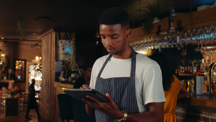 African American waiter working in restaurant on a tablet Royalty-Free Stock Footage #1088682719