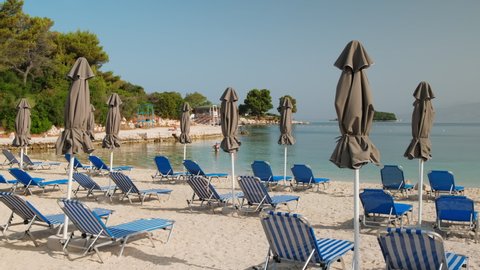 Beautiful beach with umbrellas and sunbeds at Ionian sea in Ksamil, Albania. Perfect summer vacation destination. Sunshades and sunbeds on the empty beach. 