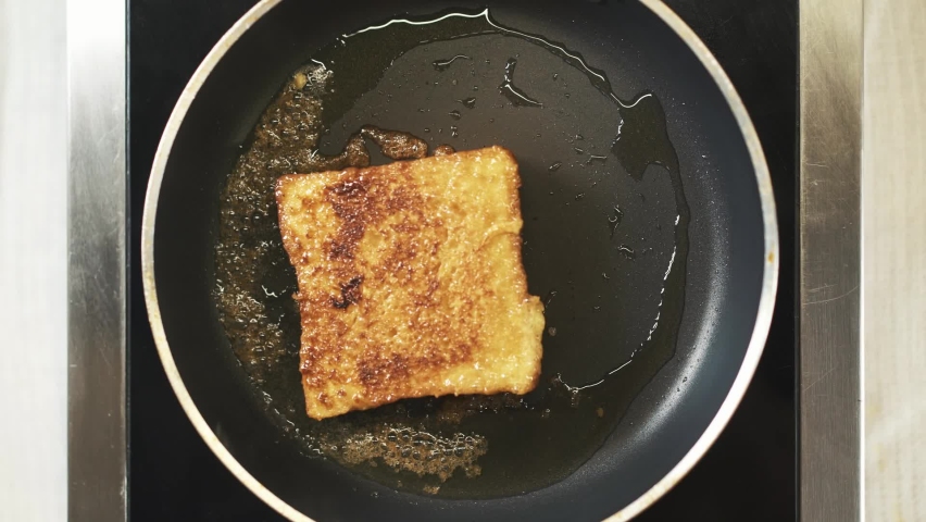 French toast being fried in ghee and sugar in a non-stick pan. Top view shot of cooking process. Easy breakfast recipe from bread. Sweet Snack  | Shutterstock HD Video #1088684091