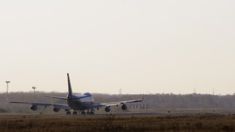 Long shot rear view, jumbo jet picks up speed and takes off. Huge double-deck four-engine plane takes off, slow motion