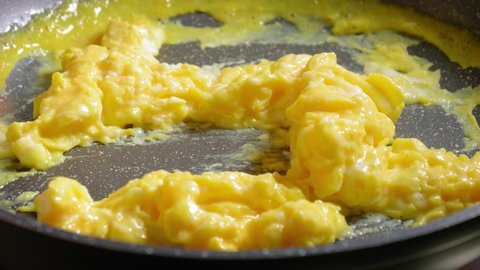Person is Stirring in Scrambled Eggs on Frying Pan, Cooking Eggs for Breakfast
