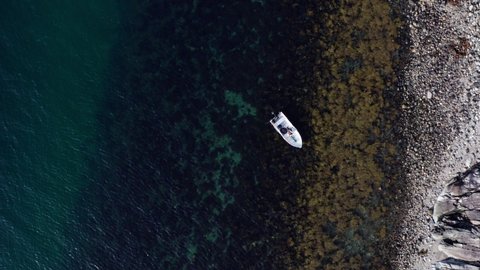 Person In Boat Paddles On Clear Blue Waters Off The Shore In Vikan, Indre Fosen, Norway. aerial top-down