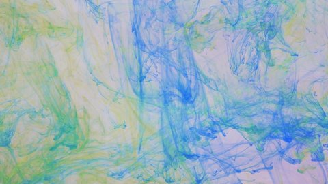 Liquid abstractions, the dissolution of blue, yellow and green paint in water.