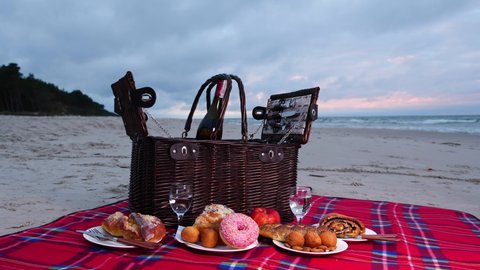 Picnic basket at the beach. Cozy and classy picnic on the sand by the sea. Summer holidays and spring break concept. Romantic dinner for couple and friends.