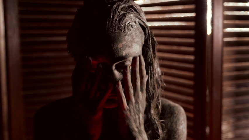 crazy woman is smearing mud over her face skin, closeup view, beauty treatment in spa salon