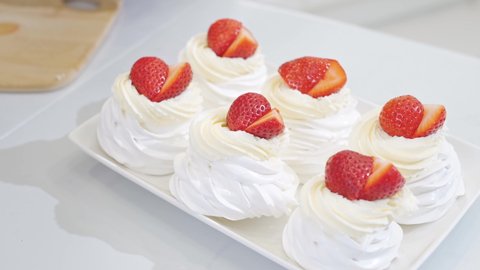 close up. woman cook decorates cakes anna pavlova with strawberries and blueberries . recipes for delicious traditional desserts. cooking school and courses. confectionery menu