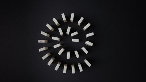
Falling dominoes. Chain reaction, built figure of dominoes falling in slow motion. View from above.