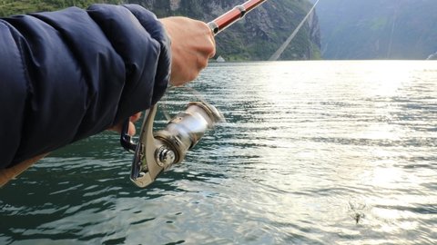 Woman fishing on Fishing rod spinning in Norway. Fishing in Norway is a way to embrace the local lifestyle. Countless lakes and rivers and an extensive coastline means outstanding opportunities...