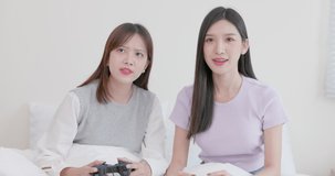 Couple of amusing young women holding controllers and playing video game together. A couple of women are playing a game, and one of them is cheating to win this round. funny video game concept