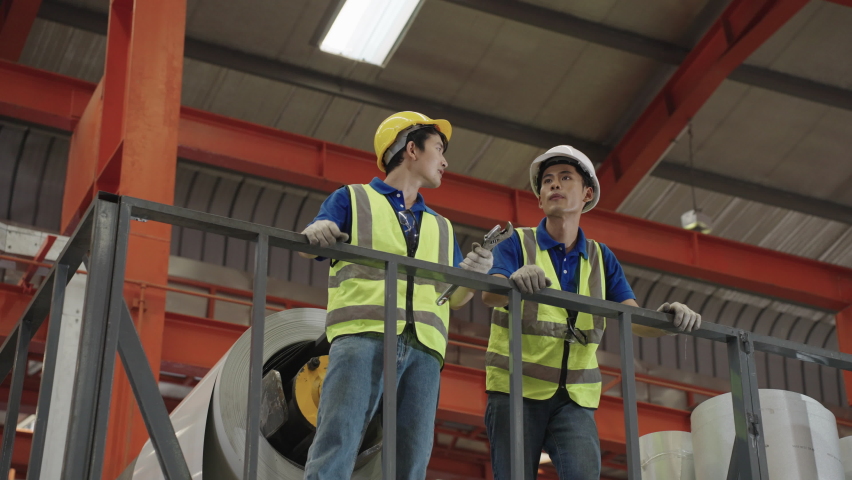 Asian workers and engineers stand on the second floor and inspect the factory maintenance plans.