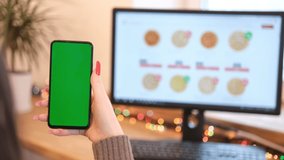 A woman orders pizza. Woman in her office is holding a smartphone with a green screen. The girl chooses pizza on the site.