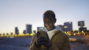 African American Man Using cell phone in the city at night. Smiling black guy with Smartphone for Social Media Dating App  - Powered by Shutterstock - Get 15% off with code: PIKWIZARD15
