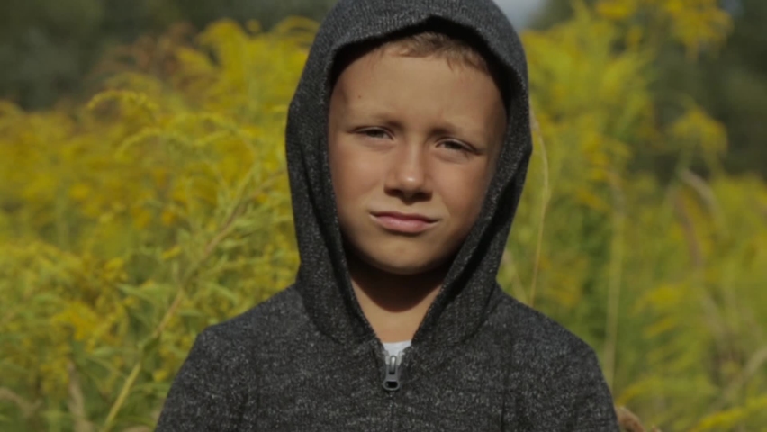 Cute boy in a grey hoodie outdoors