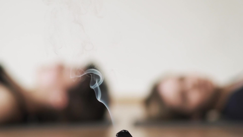 Two girl in blur lying in shavasana on Aroma therapy healing ritual for mental health and relax body. Purification Ceremony. Smoke of Palo Santo Magic Tree. Aroma of holy tree calms and relaxes | Shutterstock HD Video #1088706995