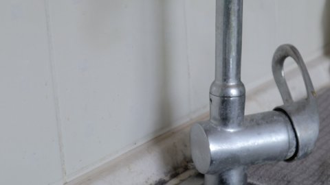 An old single lever valve with a leak. Chrome-plated basin mixer with running water on the basin.