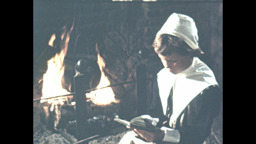 1950s: Girl in period costume reading by fire.