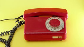 hand picks up red landline phone on yellow background. Old vintage home phone with wires and rotary dialer. Conversation on retro telephone from the 80s - Powered by Shutterstock - Get 15% off with code: PIKWIZARD15
