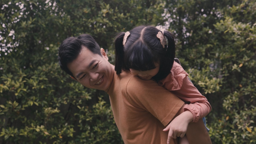 Young father giving his daughter piggyback and smiling in the outdoor park. Happy Asian parent. | Shutterstock HD Video #1088712169