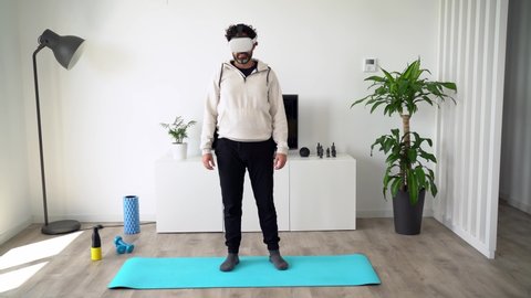 Young energetic bearded man using 360 virtual reality vision to exercise kungfu fighting in living room, enjoying the fun cyber experience of Chinese martial art sport in vr simulation reality concept