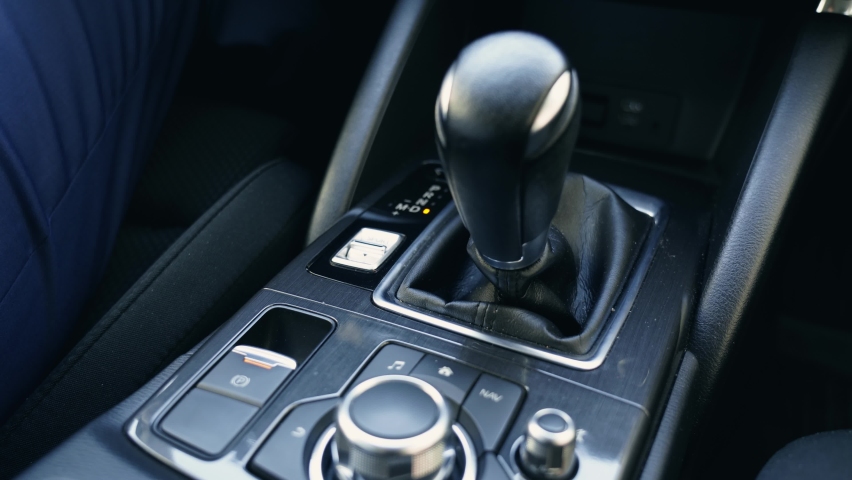 Hand female with red nails driver using automatic gear shift system in car. Woman drive an luxury car.